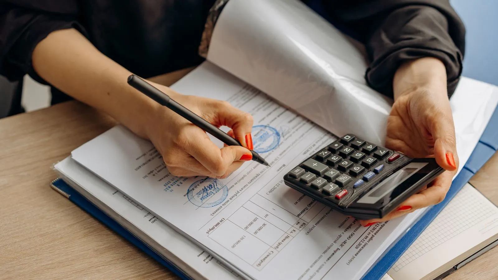 An accountant working through financial paperwork with a calculator